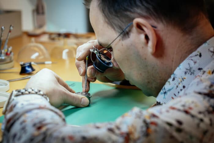 Urmakare som reparerar en klocka med lupp och liten skruvmejsel